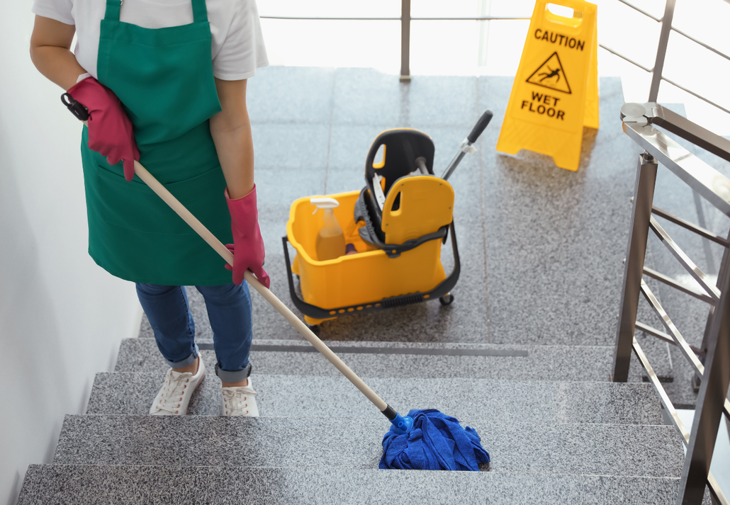A cleaner mopping stairs in an office stairwell